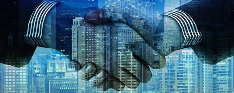 Shaking hands with buildings in background