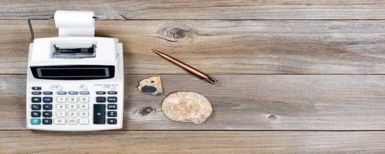 Overhead view of an adding machine and paper roll on stressed wood with stone fossils. Obsolete technology concept.