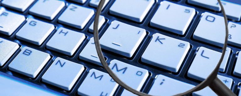 Maginified glass focussed on computer keyboard