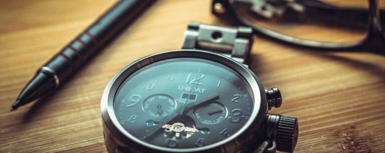 Close-up of a watch beside a black pen on a wooden table