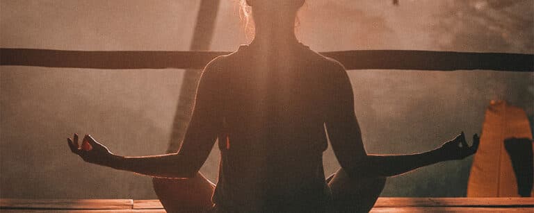 A woman performing a yoga pose during sunrise